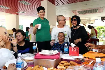 SARAPAN DENGAN PENDUDUK: Dr Fatimah (baju hijau) bersama penduduk menjamu sarapan yang disiapkan penduduk sendiri di Blok 22 Haig Road semalam. - Foto ZAOBAO