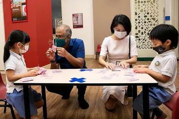 TINJAU TAJAKA: Encik Masagos Zulkifli dan Cik Sun Xueling bermesra bersama beberapa kanak-kanak semasa lawatan mereka ke pusat prasekolah Learning Vision di Pasir Panjang semalam. - Foto MSF