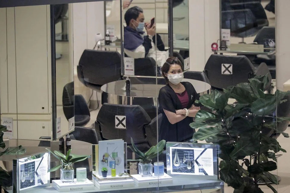 Seorang pekerja di kedai gunting rambut di Marina Bay Sands memakai pelitup, beberapa hari sebelum tempoh pemutus litar berkuatkuasa di Singapura. 