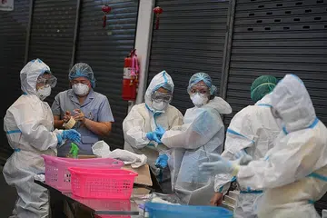 JAGA KESIHATAN DIRI: Sekumpulan pekerja penjagaan kesihatan semalam bersiap sedia untuk mengangkat sampel untuk ujian lanjut di Pasar Thanon Mitr, Bangkok, Thailand, dalam usaha membendung penularan Covid-19 di negara itu. - Foto AFP