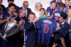 Presiden Perancis, Emmanuel Macron (depan, dua dari kanan) dan presiden Paris Saint Germain (PSG) Nasser al-Khelaifi (kanan) memegang jersi PSG ketika pemain pertahanan PSG, Marquinhos (kiri), memegang trofi Liga Juara-Juara semasa sambutan kemenangan mereka di Istana Élysée pada 1 Jun. Namun, Macron mengecam para peminat yang keterlaluan menyambut kemenangan tersebut hingga timbul keganasan semasa sambutan mereka di kota Paris.