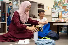 BERSIAP SEDIA: Cik Siti Ummu Aidilah Badar mengajar anaknya Muhammad Al-Zaim Muhammad Shafiq, enam tahun, cara mengemas begnya untuk Darjah 1.