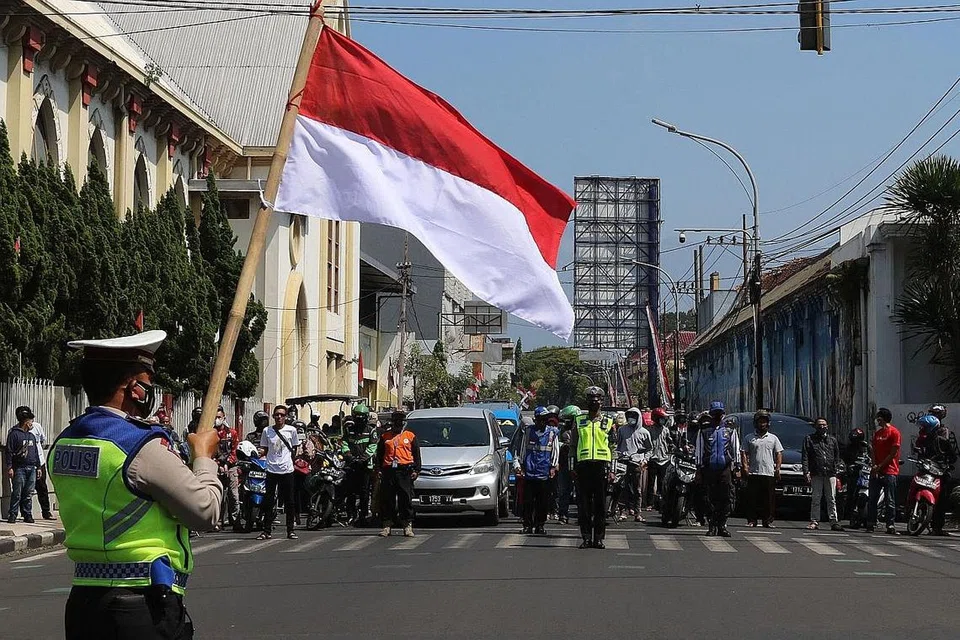 UPACARA NAIKKAN BENDERA: Satu upcara menaikkan bendera sempena sambutan Hari Kemerdekaan Indonesia ke-76 diadakan di istana Presiden di Jakarta semalam. Di beberapa jalan raya di bandar-bandar utama seperti Malang (gambar atas), penunggang motosikal dan pemandu kenderaan turut berhenti seketika sebagai tanda hormat kepada kibaran bendera. - Foto-foto REUTERS, AFP