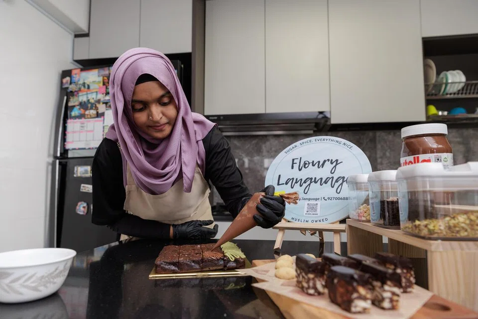 Cik Rahmathunnisa Mohamed Maideen menggunakan pek panas bagi melegakan kesakitan sendi ketika menyediakan kek dan biskut