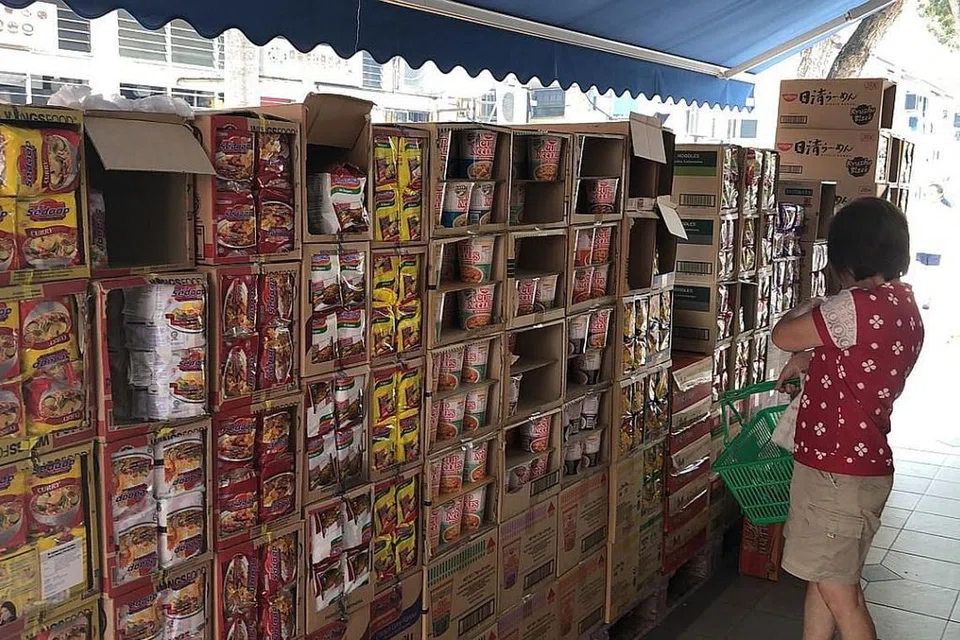 STOK MENCUKUPI: Kotak-kotak yang mengandungi mi segera ini diletakkan di hadapan cawangan NTUC FairPrice di Whampoa semalam. - Foto BH oleh CARA WONG