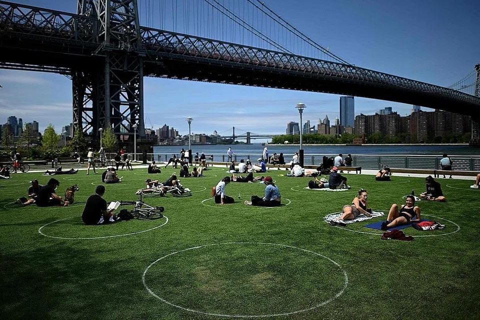 BERSANTAI DALAM JARAK SELAMAT: Pengunjung bersantai di Taman Domino di New York City, Amerika Syarikat, sambil memastikan jarak selamat dengan mengehadkan diri mereka pada bulatan putih. - Foto AFP