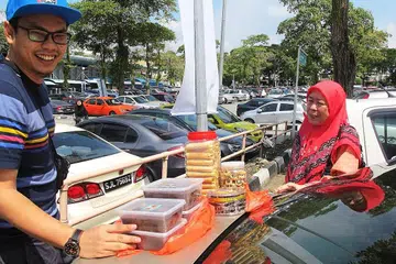 BELANJA SAMBIL NIKMATI SUASANA RAYA: Cik Zahirah dan anaknya, Encik Muhammad, bersama juadah Raya berupa kuih-muih dan kek kukus yang mereka beli di Pasar Larkin Sentral. - Foto-foto BM oleh SAINI SALLEH