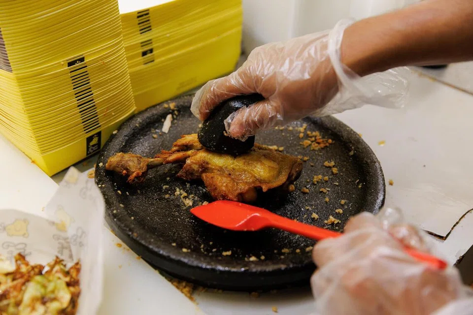 Setelah ayam digoreng, ia dipenyet di batu lesung.