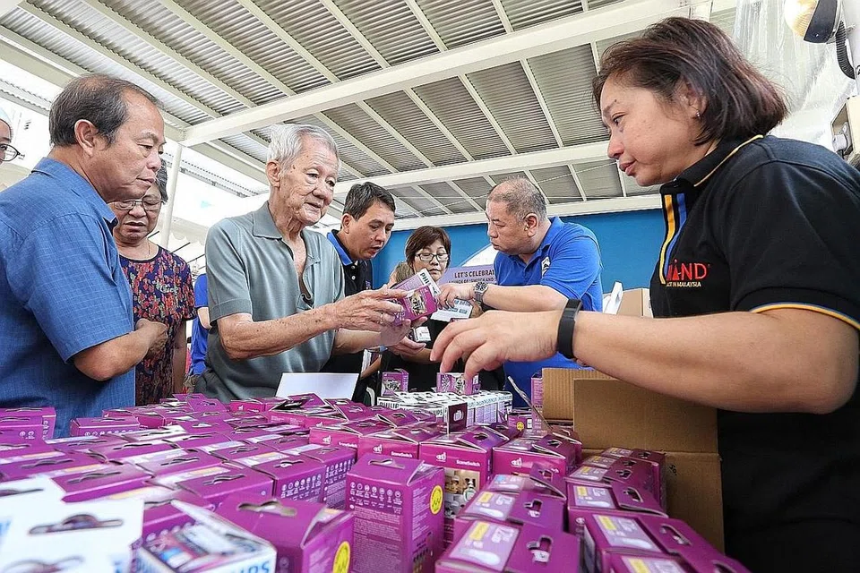 TUKAR KE LED:Penduduk Blk 621A Punggol Central mendapatkan bal lampu LED semasa pelancaran kempen SSUL pada Ogos 2018. - Foto ZAOBAO