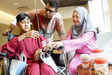 TETAP MAHU BERAYA: Syaqir Ali, yang telah hampir tiga bulan dirawat di Hospital Mount Elizabeth Novena akibat masalah paru-paru akibat sepsis, meminta ibu bapanya, Encik Mohd Ali dan Cik Siti Huzainawati, membelikannya baju Melayu baru untuk menyambut Raya. - Foto JOHARI RAHMAT