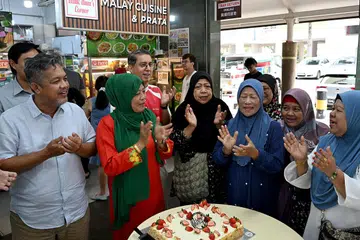 Anggota Parlimen (AP) GRC Nee Soon, Profesor Madya Dr Muhammad Faishal Ibrahim (tengah berbaju merah), meraikan hari lahir seorang penduduk Nee Soon, Cik Siti Rodziah Pauzan (barisan depan, dua dari kanan) yang juga pemilik Mak Itam’s Corner, sebuah gerai kedai kopi di Yishun, pada 15 Februari.
