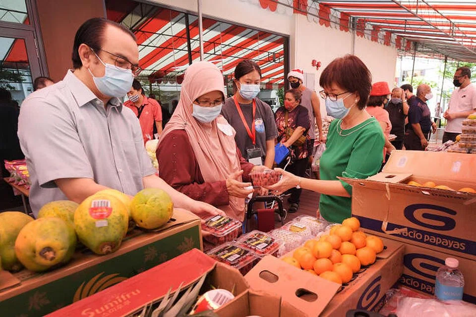 ACARA AGIH MAKANAN: Mayor Majlis Pembangunan Masyarakat (CDC) Central Singapore, Cik Denise Phua (kanan) dan Presiden Jamiyah, Prof (Adj) Dr Mohd Hasbi Abu Bakar (kiri), membantu seorang penduduk memilih buah-buahan yang disediakan oleh Bank Makanan Jamiyah.
