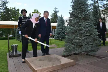 PERKUKUH HUBUNGAN: Presiden Halimah Yacob menanam pokok di Lorong Tetamu Kehormat di Istana Kuksaroy di Uzbekistan pada Rabu dengan disaksikan Presiden Uzbekistan, Encik Shavkat Mirziyoyev.