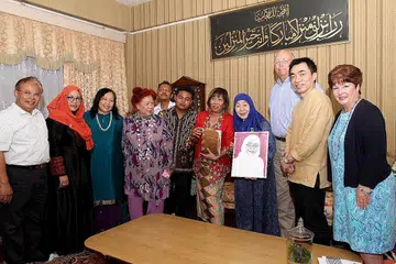 RAKAM TAHNIAH: Puan Noor Aishah (empat dari kanan), dua bekas pelajar Sekolah Menengah Yusof Ishak - Dr Elias Tam (dua dari kanan) dan Cik Latifah Ali (lima dari kanan) - serta Pengarah Sekolah Masyarakat Antarabangsa, Encik John Kennedy (tiga dari kanan), menandatangani kad dan ingin menghadiahkan potret kepada Presiden Halimah Yacob sebagai ucap tahniah atas pencapaiannya sebagai presiden wanita pertama Singapura. - Foto SHAHRIYA YAHAYA