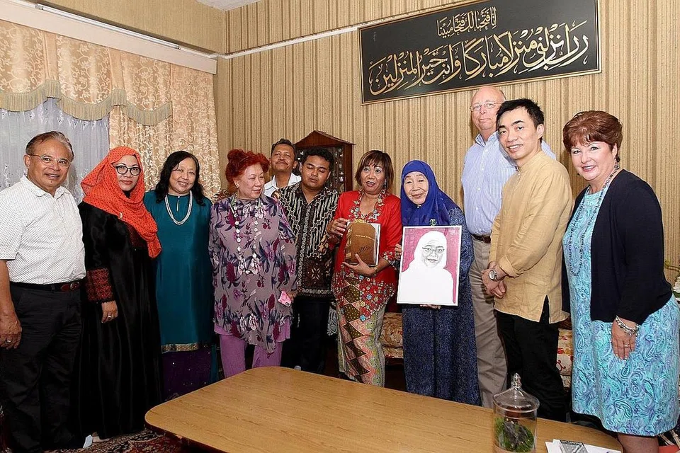 RAKAM TAHNIAH: Puan Noor Aishah (empat dari kanan), dua bekas pelajar Sekolah Menengah Yusof Ishak - Dr Elias Tam (dua dari kanan) dan Cik Latifah Ali (lima dari kanan) - serta Pengarah Sekolah Masyarakat Antarabangsa, Encik John Kennedy (tiga dari kanan), menandatangani kad dan ingin menghadiahkan potret kepada Presiden Halimah Yacob sebagai ucap tahniah atas pencapaiannya sebagai presiden wanita pertama Singapura. - Foto SHAHRIYA YAHAYA