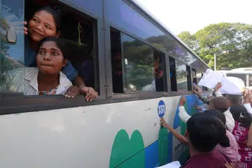 Saudara-mara dan rakan-rakan memegang sepanduk semasa mereka berkumpul di sekeliling bas yang membawa banduan yang dibebaskan dari penjara Insein di Yangon, Myanmar, pada 4 Januari 2025. Tentera Myanmar mengumumkan pengampunan kepada lebih 5,000 tahanan di seluruh negara pada 4 Januari untuk menandakan Hari Kemerdekaan.
