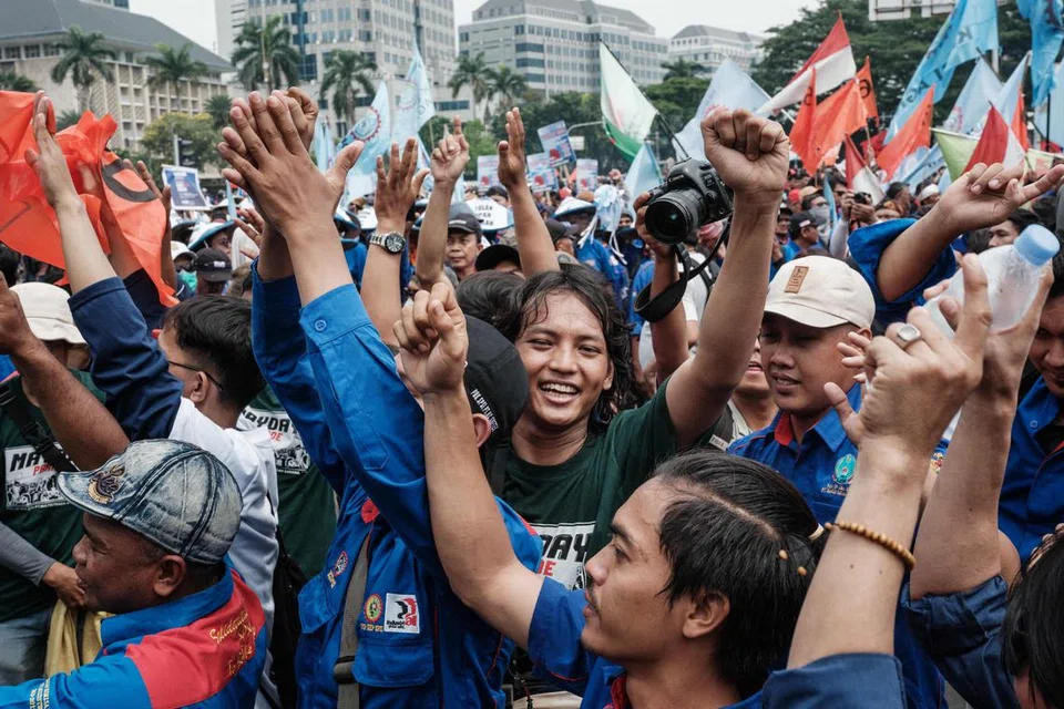 Penunjuk perasaan memegang sepanduk dan bendera dalam perhimpunan menyambut Hari Pekerja pada 1 Mei di Jakarta.