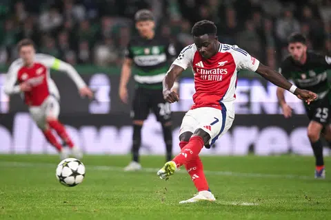 Pemain tengah Arsenal, Bukayo Saka (tengah), menyempurnakan sepakan penalti untuk menjaringkan gol keempat Arsenal melawan Sporting CP pada 26 November. Ia menyaksikan Arsenal menang 5-1.