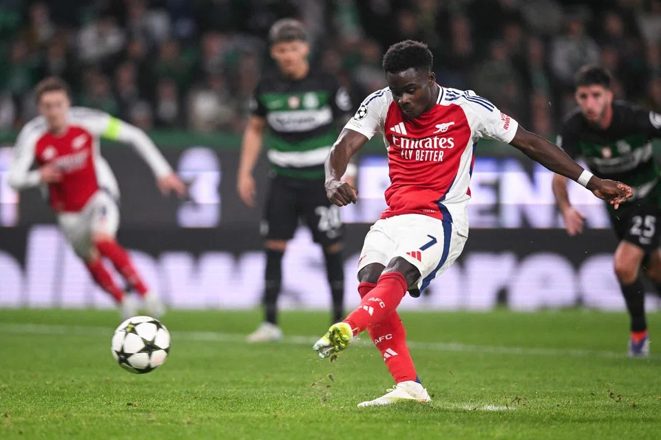 Pemain tengah Arsenal, Bukayo Saka (tengah), menyempurnakan sepakan penalti untuk menjaringkan gol keempat Arsenal melawan Sporting CP pada 26 November. Ia menyaksikan Arsenal menang 5-1.