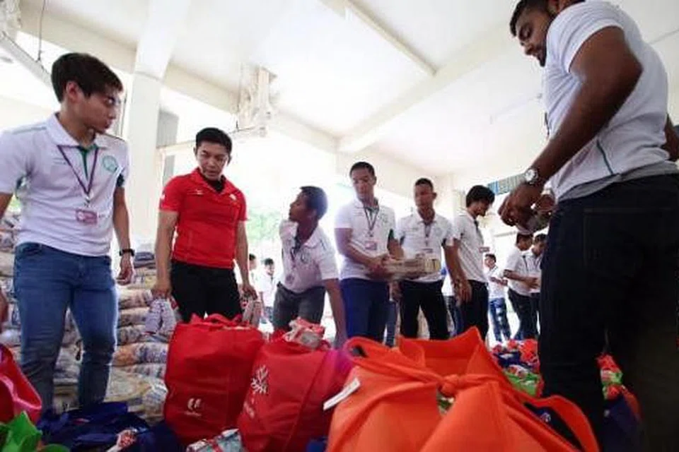 HULUR BANTUAN: Pemain Geylang Gabriel Quak (kiri) dan Faritz Hameed (kanan) bersama Menteri Pembangunan Sosial dan Keluarga, Encik Tan Chuan-Jin (baju merah), kelmarin. - Foto ONE COMMUNITY
