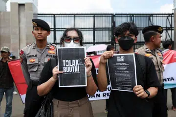 Penunjuk perasaan memegang poster sebagai tanda protes di luar bangunan Parlimen Indonesia terhadap rang undang-undang ketenteraan kontroversi yang akan memperuntukkan lebih banyak jawatan awam kepada pegawai tentera, di Jakarta, Indonesia, pada 20 Mac 2025.