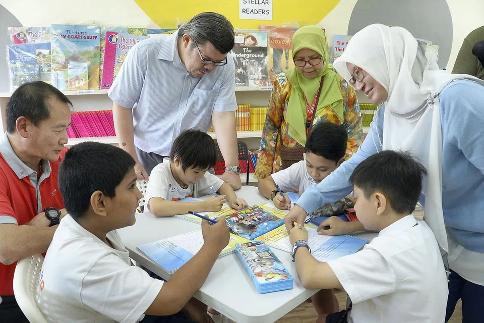PROGRAM KESELAMATAN SIBER: (Dari kiri) Encik Andrew Buay dari Singtel; Encik Patrick Aw, guru ICT APSN Chaoyang School; Cik Yazilah Amir, pengetua APSN Chaoyang School; dan Cik Siti Anita Rahmat, naib pengetua, membantu pelajar menyelesaikan tugas dalam buku kerja mereka yang menggariskan panduan tentang keselamatan dalam talian. - Foto JOHARI RAHMAT