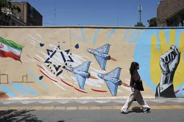 Seorang wanita Iran berjalan di hadapan mural anti-Israel di sebuah jalan raya di Teheran pada 30 Mei 2026.
