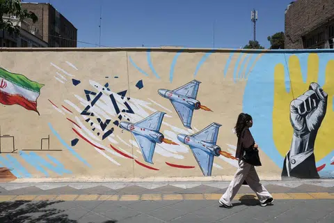 Seorang wanita Iran berjalan di hadapan mural anti-Israel di sebuah jalan raya di Teheran pada 30 Mei 2026.