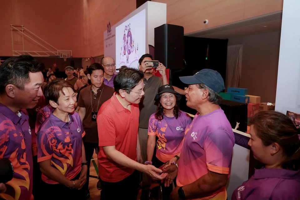 Perdana Menteri Encik Lawrence Wong beramah mesra dengan suakrelawan Team Nila, Encik Zainuddin Mohamed Adam (memakai topi), di Karnival Team Nila di Pusat Sukan ActiveSG Bukit Canberra pada 8 Mac. Beliau turut ditemani (dari kiri) Setiausaha Parlimen Kanan (Kebudayaan, Masyarakat dan Belia merangkap Pembangunan Sosial dan Keluarga), Encik Eric Chua; Menteri Kemampanan dan Sekitaran, Cik Grace Fu. 
