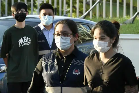 Pasangan suami isteri yang terlibat dalam penipuan barangan mewah, Pi Jiapeng dan Pansuk Siriwipa, diiringi pegawai polis di Pusat Pemeriksaan Woodlands pada 11 Ogos 2022.