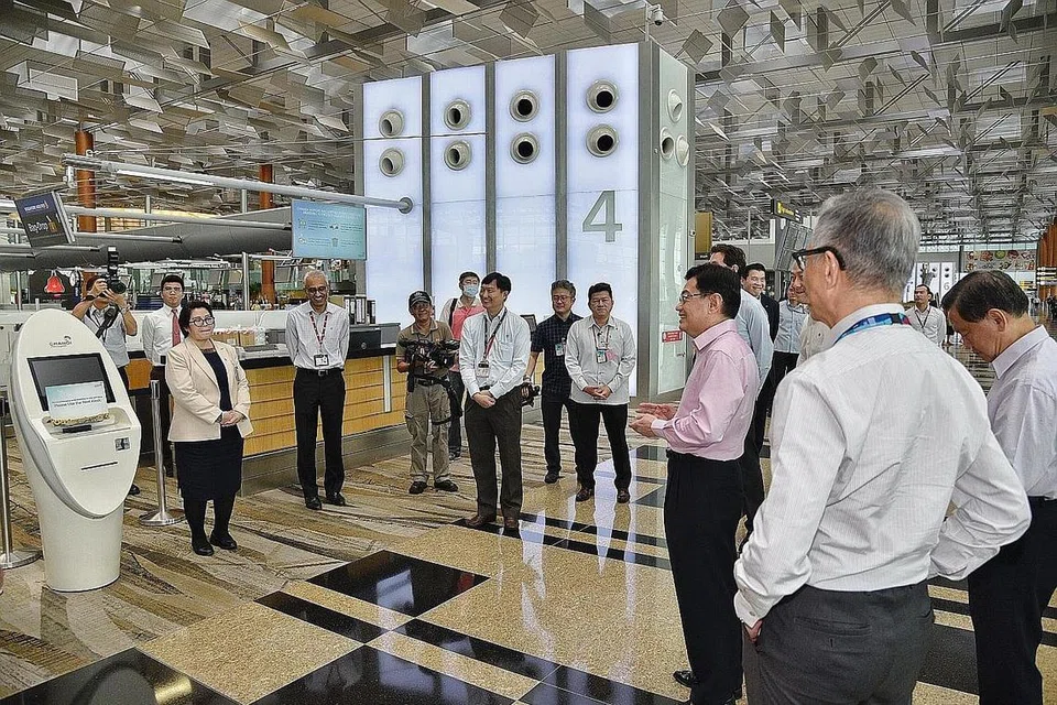 PANTAU SEKTOR PENERBANGAN: Encik Heng (kemeja merah jambu) bertemu beberapa kakitangan sektor penerbangan di Lapangan Terbang Changi semalam. - Foto BH oleh DESMOND WEE