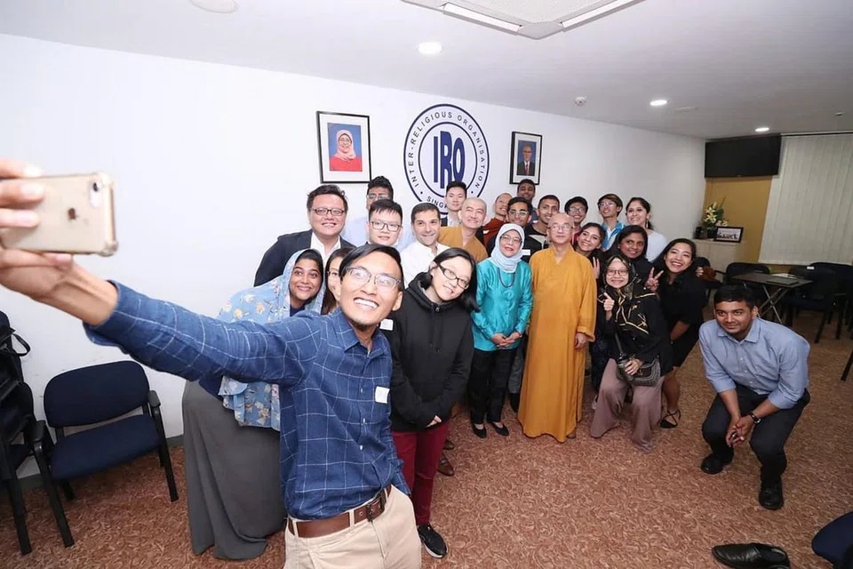 PERPADUAN SILANG AGAMA: Pemimpin belia IRO, Encik Mohamad Saiful Md Anuar , sedang berswafoto dengan Presiden Halimah Yacob (tengah) yang berdiri bersama presiden IRO, Encik Ben J. Benjamin (di kanan Puan Halimah) dan naib presiden IRO, Venerable Seck Kwang Phing (di kiri Puan Halimah), serta peserta lain di sesi pertama 'Untitled Conversations' kelmarin. - Foto MCI