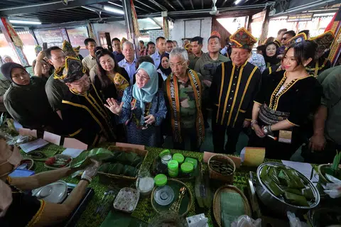 CUBA MAKANAN TRADISIONAL: Sultan Abdullah Ahmad Shah dan Tunku Azizah Aminah Maimunah Iskandariah (tiga dan empat dari anan) mencuba pelbagai jenis makanan tradisional ketika melawat Perkampungan Budaya, Persatuan Kebudayaan Kadazadusun (KDCA) Penampang di Sabah.