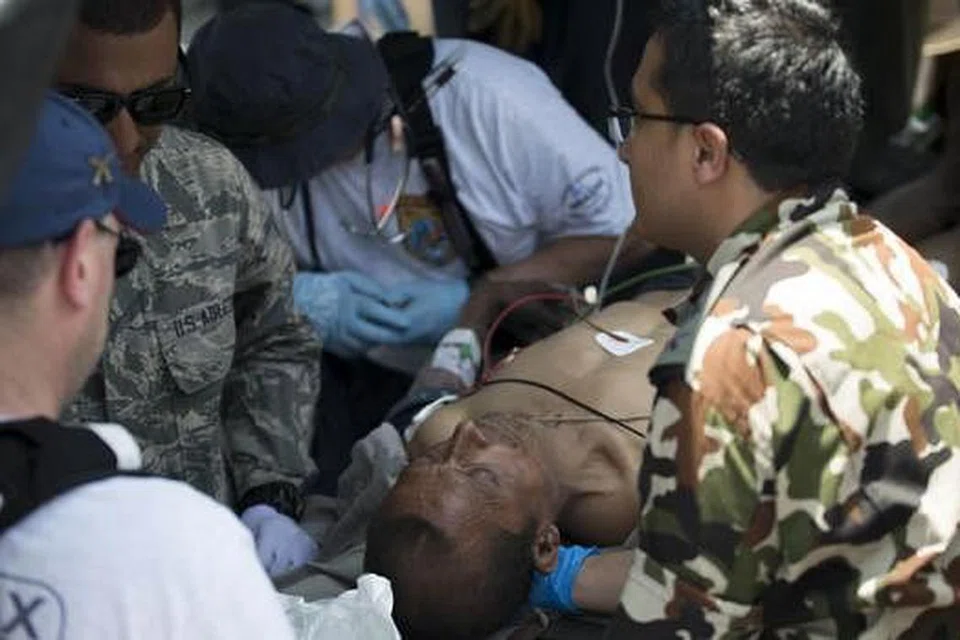 BERIKAN BANTUAN: Tentera Amerika dan tentera Nepal membantu seorang lelaki Nepal yang cedera semalam akibat gempa bumi terbaru yang melanda Nepal. - Foto AFP