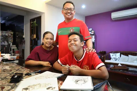 LEBIH YAKIN: Nuh Syazwan (kanan) tidak pernah jadikan masalah disleksia sebagai hambatan baginya melakukan kegiatan melukis yang merupakan hobinya. Dia sering dapat sokongan keluarga termasuk ibu bapanya, Encik Muhammad Zulkarnaen dan ibunya Cik Siti Zakiah. - Foto BH oleh GAVIN FOO