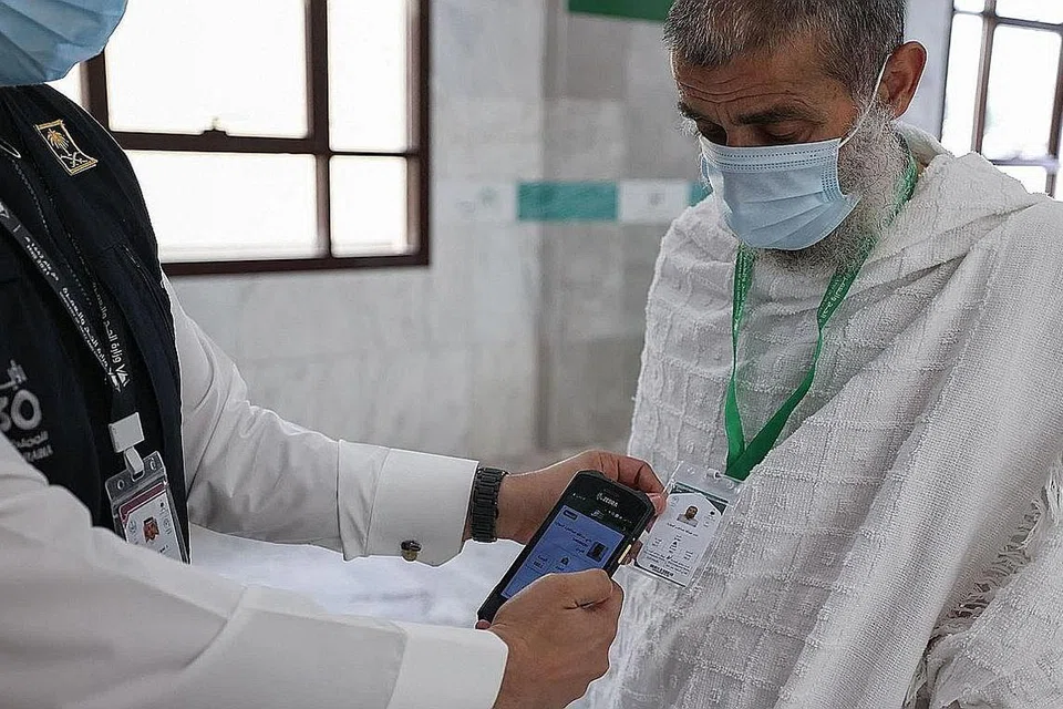 PERMUDAH PROSES: Seorang anggota Saudi mengimbas kad haji seorang anggota jemaah yang membolehkan akses tanpa sentuhan ke tapak suci, tempat penginapan dan pengangkutan. - Foto AFP 