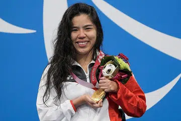 PINGAT EMAS DALAM GENGGAMAN: Perenang Singapura Yip Pin Xiu di atas podium meraikan kemenangannya bagi acara kuak lentang 100 meter di Pusat Akuatik Tokyo, semalam. - Foto AFP