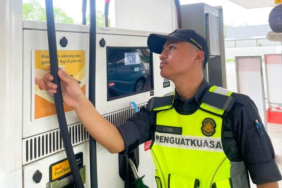 Pegawai Penguat Kuasa Kementerian Perdagangan Dalam Negeri dan Kos Sara Hidup memeriksa pam minyak.