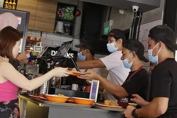 GUNAKAN PELITUP: Kakitangan di restoran Rumah Makan Minang di Kandahar Street mengambil langkah berjaga-jaga dengan menggunakan pelitup muka semasa bekerja. - Foto BH oleh AZMI ATHNI