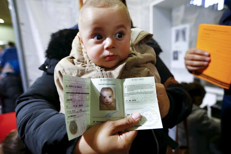 DAPAT SUAKA: Cik Asma Al Saleh, 33 tahun, mendukung anak lelakinya Ibrahim berusia lima bulan dengan dokumen awal pendatang rasmi Jerman "Ankunftsnachweis", sebuah khemah sementara di barat Jerman.