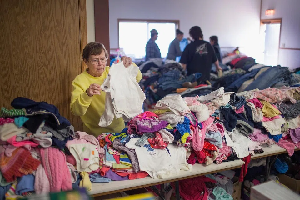 PILIH PAKAIAN: Salah seorang mangsa kebakaran hutan yang terpaksa meninggalkan rumahnya di Fort McMurray memilih pakaian untuk dipakai di pusat perpindahan mangsa kebakaran hutan di Alberta. - Foto AFP