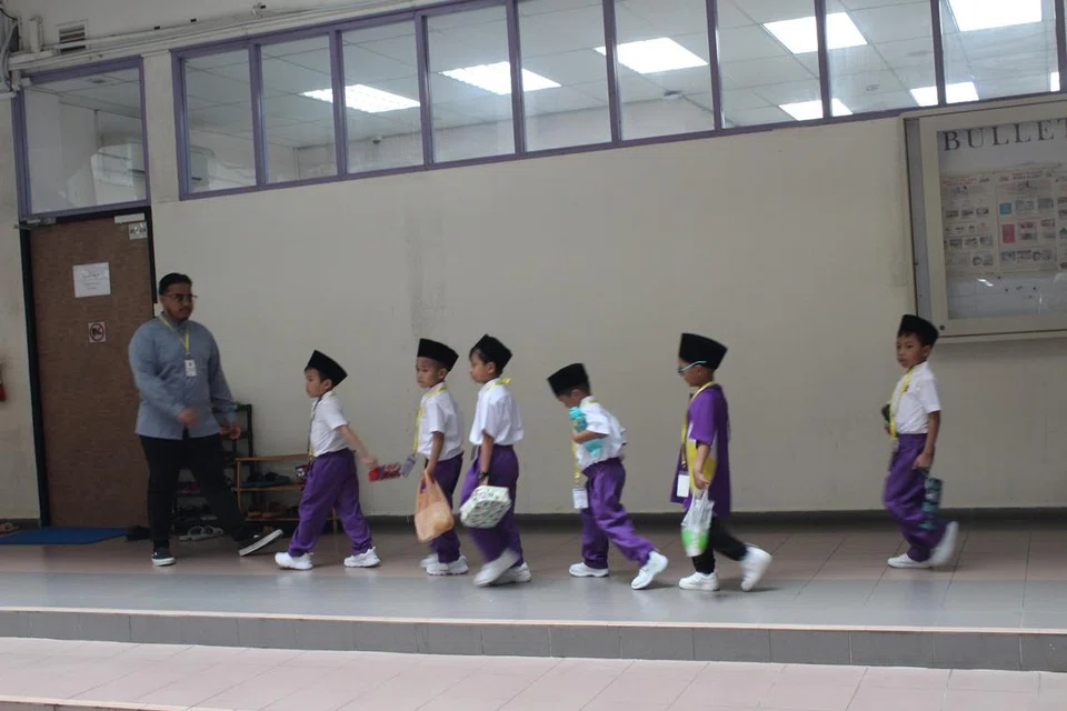 Pelajar darjah satu ketika memulakan pembelajaran mereka dan ditemani oleh bekas pelajar (kiri) pada awal pembukaan sekolah pada Januari 2024. 