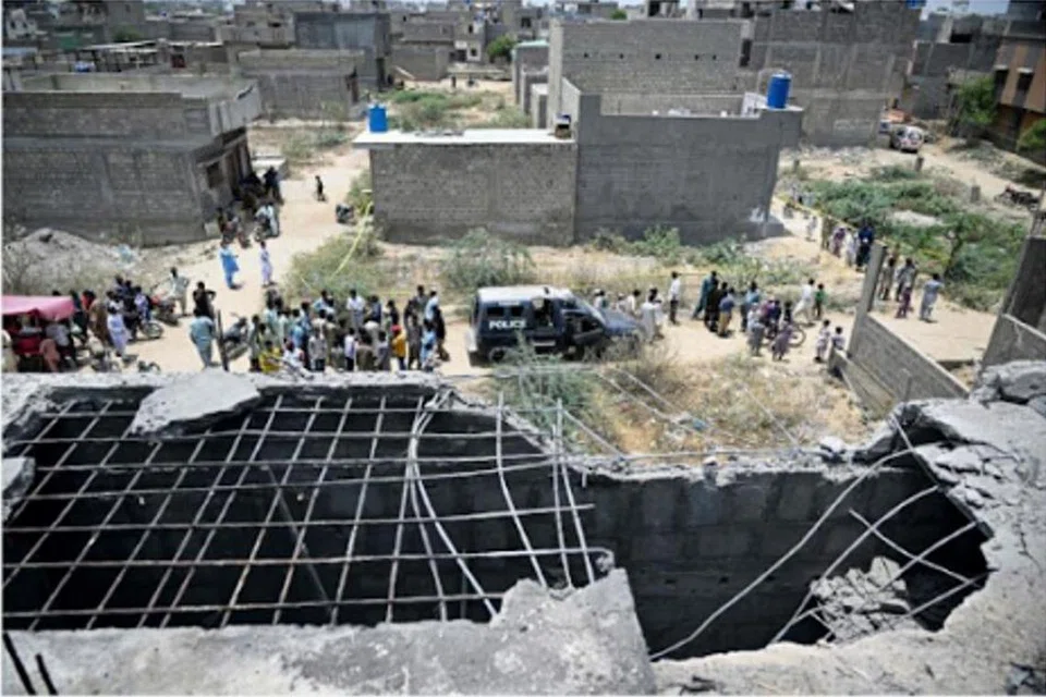 Penduduk berkumpul ketika anggota polis menjalankan pemeriksaan pada 8 Mei 2025, di tapak yang kelihatan seperti lubang besar tempat sebuah dron dipercayai ditembak jatuh di Karachi, Pakistan.