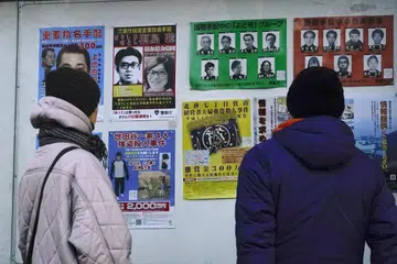 Sekeping foto lelaki bernama Satoshi Kirishima sedang tersenyum dipaparkan pada poster orang dikehendaki di luar balai polis di seluruh Jepun. Selepas 50 tahun, pihak berkuasa yakin mereka telah menemui individu yang dicari selama ini.