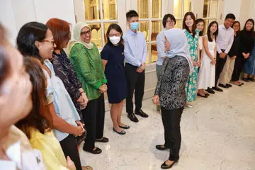 UCAPKAN TERIMA KASIH: Presiden Halimah Yacob dilihat membuat setiausahanya, Cik Katija Beevee (baju hijau), tertawa semasa berbual dan  mengucapkan terima kasih kepada kakitangan Istana pada hari terakhirnya sebagai Presiden pada 13 September. 