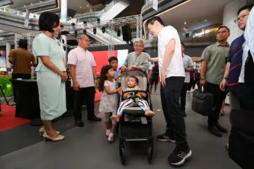 Perdana Menteri Lawrence Wong (kanan) beramah mesra dengan Encik Noor Ain Abdul Rahman dan cucunya, sempena acara memperingati ulang tahun ke-10 SGSecure di Our Tampines Hub pada 23 September. Bersama mereka ialah (dari kiri) Menteri Kedua (Ehwal Dalam Negeri merangkap Ehwal Luar), Cik Sim Ann dan Menteri Undang-Undang merangkap Menteri Kedua Ehwal Dalam Negeri, Encik Edwin Tong.