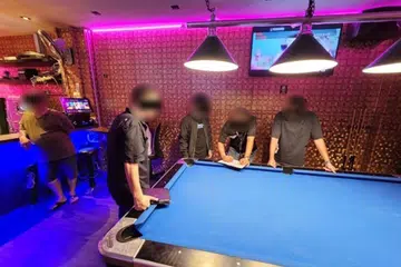 DIPERIKSA: Beberapa individu diperiksa pegawai polis di sebuah pusat hiburan awam di 211 Geylang Road.