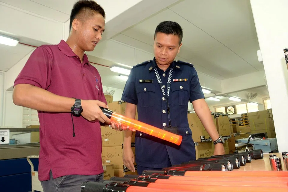 SALING KERJASAMA: DSP Rimyzad (kanan) memastikan polis mempunyai kelengkapan sesuai ketika bertugas, misalnya waktu Pilihan Raya Kecil Bukit Batok baru-baru ini. Bersamanya ialah pengurus kelengkapan kejuruteraan, Encik Khairul Anshar. - Foto JOHARI RAHMAT