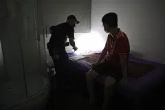DISOAL: Seorang lelaki, dipercayai pelanggan, kelihatan sedang disoal siasat oleh pegawai polis tidak beruniform dalam sebuah bilik di cawangan urut badan di Balestier Road yang disyaki menawarkan khidmat seks secara sulit. - Foto BH oleh JASON QUAH