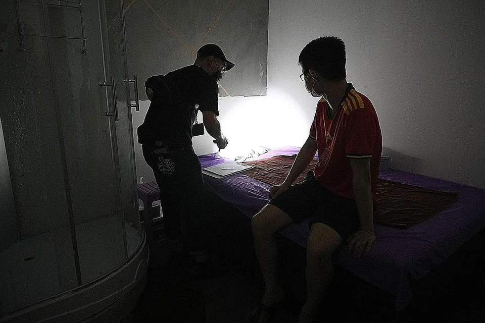 DISOAL: Seorang lelaki, dipercayai pelanggan, kelihatan sedang disoal siasat oleh pegawai polis tidak beruniform dalam sebuah bilik di cawangan urut badan di Balestier Road yang disyaki menawarkan khidmat seks secara sulit. - Foto BH oleh JASON QUAH